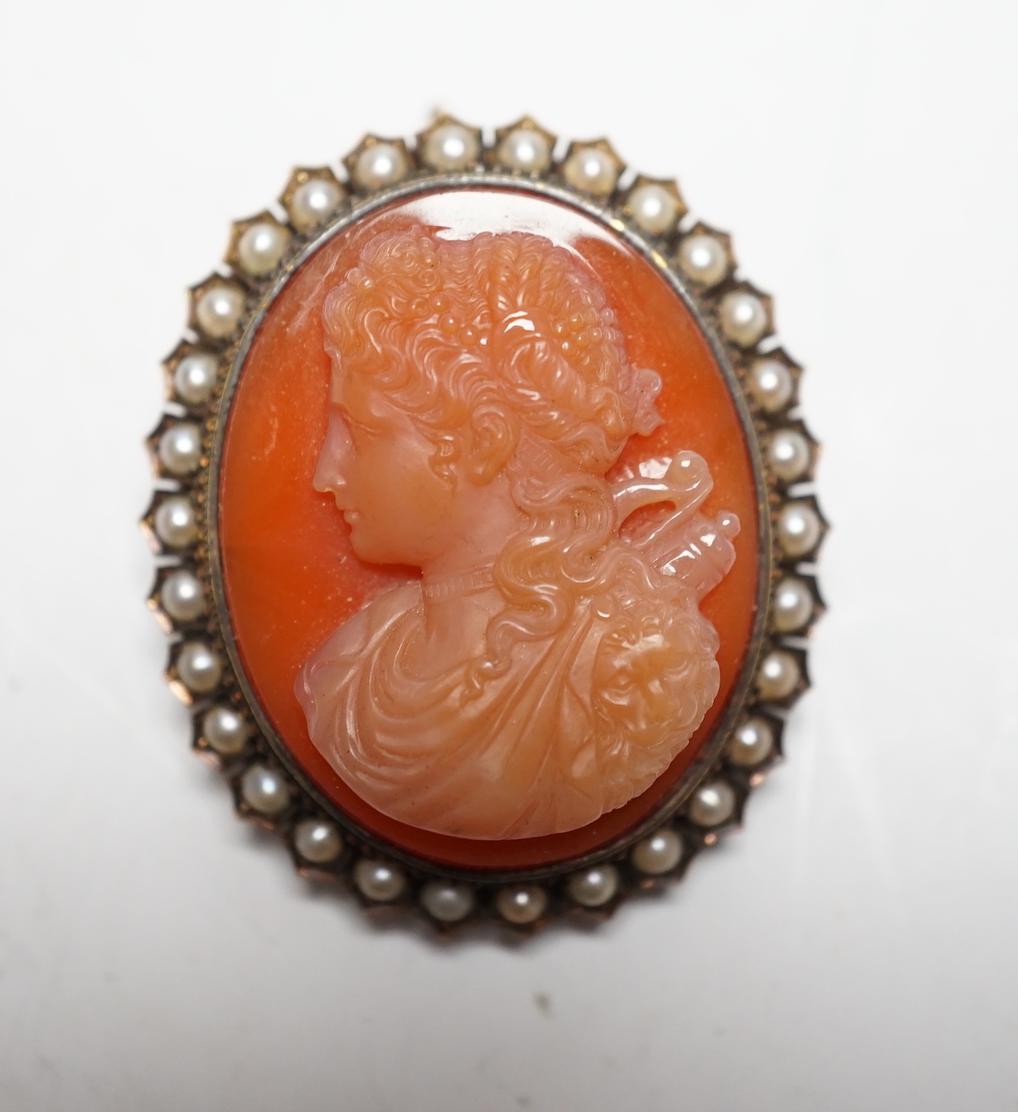 A Victorian yellow metal, and seed pearl mounted oval hardstone cameo pendant brooch, carved with the bust of a lady to dexter, 39mm.